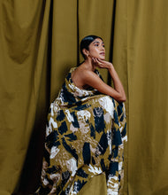 Load image into Gallery viewer, Model crouched on platform wears Atelier Brunette's Mira Viscose fabric draped across body, like an asymmetrical maxi dress