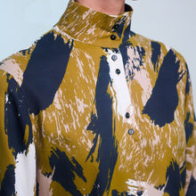 Load image into Gallery viewer, Close-up of model wearing a stand collar, button-up shirt made in Atelier Brunette's Mira Viscose fabric.