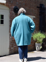 Load image into Gallery viewer, Back view of lady in front of a wooden door wearing a cocoon shaped Wimborne coat, above knee lenght
