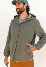 Load image into Gallery viewer, Model wears a hooded Beachcomber Jacket fastened up, with two patch pockets at chest, and two inset welt pockets