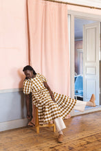 Load image into Gallery viewer, Lady sits on chair wearing a gingham dress with large bottom ruffle tier
