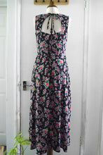 Load image into Gallery viewer, Back view of sleeveless dress hole detail at back, with ties at neck displayed on mannequin; made with Floral Viscose fabric