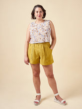 Load image into Gallery viewer, Model wears Sepia Shorts with hand in large patch pocket. Paperbag, drawstring waist fastening.