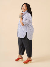 Load image into Gallery viewer, Lady wears oversize style button up shirt with the collar styled to be stood up, scooped hem slightly longer at the back hits thigh level
