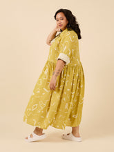 Load image into Gallery viewer, Side view of lady wearing a loose fit dress with top button up shirt, long sleeves rolled up, with skirt gathered at waist, midi length
