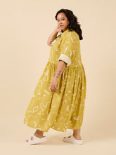 Load image into Gallery viewer, Side view of lady wearing a loose fit dress with top button up shirt, long sleeves rolled up, with skirt gathered at waist, midi length