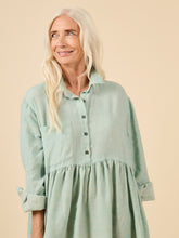 Load image into Gallery viewer, Close up of top detail of lady wearing a loose fit dress with top button up shirt with long sleeves rolled up, skirt gathered at waist.
