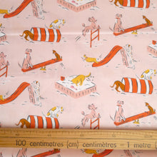 Load image into Gallery viewer, Organic cotton fabric displayed flat, shows a wooden ruler next to print of cartoon dogs playing on playground apparatus