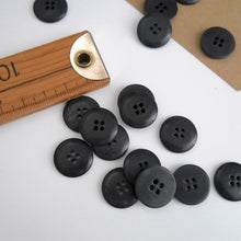 Load image into Gallery viewer, Scattering of 4-hole buttons displayed next to wooden ruler