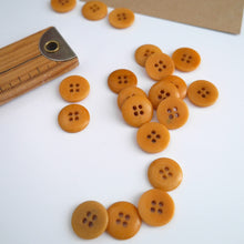 Load image into Gallery viewer, Scattering of 4-hole buttons displayed next to wooden ruler