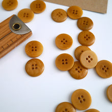 Load image into Gallery viewer, Scattering of 4-hole buttons displayed next to wooden ruler