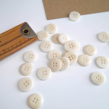 Load image into Gallery viewer, Scattering of 4-hole buttons displayed next to wooden ruler