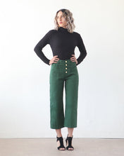 Load image into Gallery viewer, Lady wears the 3/4 length Lander Pant, highwaisted with visible button fly front and side patch pockets