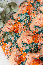 Load image into Gallery viewer, Viscose fabric shown close up, with soft drape, in a print pattern of blooming flowers