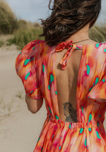 Load image into Gallery viewer, Back view of lady wearing a short-sleeve dress with centre back opening at the top with tie fastening at neck. Elasticated waistband for skirt