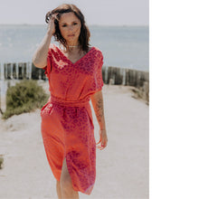 Load image into Gallery viewer, Lady at the beach walks, wearing a V-neck, short sleeved, knee length dress with waist tie
