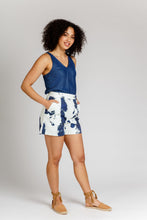 Load image into Gallery viewer, Lady wears a pair wide-leg shorts with pleats at waist, hands in side pockets