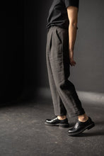 Load image into Gallery viewer, Side view of lady wearing peg trousers with front pleats and angled side pockets, with turn ups