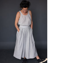 Load image into Gallery viewer, Lady wears a pleated Shepherd Pattern skirt with hands in pockets