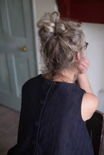 Load image into Gallery viewer, Back view of model sitting, to show off sleeveless Trapeze top, with buttons down the centre-back opening