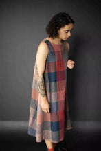 Load image into Gallery viewer, Model stands facing down, wearing the Trapeze dress, a sleeveless flared dress