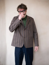 Load image into Gallery viewer, Model wears a striped jacket and dark trousers against a plain background