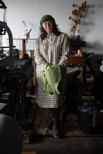 Load image into Gallery viewer, Model wears a chequered shirt dress stands in a workshop, holding a Chore Jacket over hands