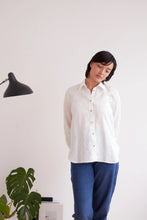 Load image into Gallery viewer, Model stands wearing a collared button-up shirt