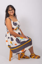 Load image into Gallery viewer, Model sat on chair wearing a sleeveless dress, with rounded neckline, elasticated waistline