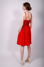 Load image into Gallery viewer, Back view of model wearing a strappy knee-length dress with elasticated back, hands in side pockets