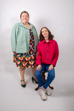 Load image into Gallery viewer, Two models wear a loose-fitting jacket with sunburst tucks around the neckline, and patch pockets. One model worn fastened, the other worn open