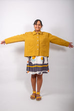 Load image into Gallery viewer, Model stands with arms out, wearing a loose-fitting jacket with sunburst tucks around the neckline, and patch pockets, worn fastened