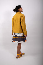 Load image into Gallery viewer, Side/Back view of model wearing a loose-fitting jacket with sunburst tucks around the neckline