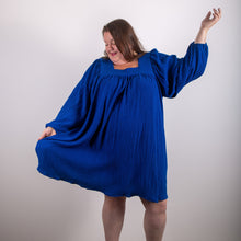 Load image into Gallery viewer, Model captured mid pose, wearing a loose-fitting dress gathered to a square neckline, with long voluminous sleeves. Above-knee length.