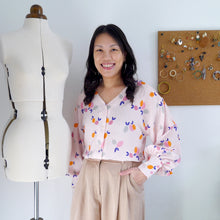 Load image into Gallery viewer, Lady wears a Nexus blouse made with a stripe with lemon print fabric. Stands next to mannequin.