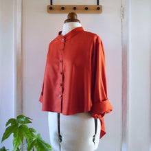 Load image into Gallery viewer, Displayed on mannequin is a cropped shirt, with band collar and fold up sleeves, made in Viscose Twill fabric