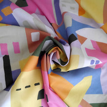 Load image into Gallery viewer, Cotton Lawn fabric with a colourful abstract pattern of geometric shapes resembling buildings, displayed with central swirl