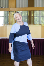 Load image into Gallery viewer, Lady wears an elbow sleeve, knee length jersey dress made up in asymmetrical block shapes