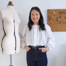 Load image into Gallery viewer, Lady wears a gathered neckline blouse made with organic cotton voile fabric, tucked into jeans.