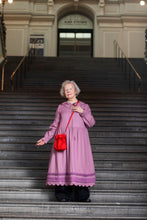 Load image into Gallery viewer, Model on steps, wears collared dress with scalloped hem with trim detail, long sleeves