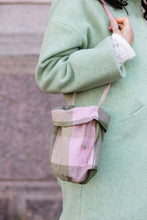 Load image into Gallery viewer, Close up detail of bag; model carries a small fabric bag, over the shoulder with thin fabric strap. Bag has fold up hem with fabric drawstrings seen peeping out underneath.