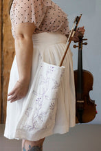 Load image into Gallery viewer, Model holds a violin, wearing a pleated knee-length skirt with a deep patch pocket, holding the violin bow