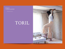 Load image into Gallery viewer, Magazine spread features a bold title: "Toril" alongside photo of lady standing on bed showing off wide legged trousers with ruffle hem