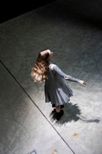Load image into Gallery viewer, Above view of model mid-twirl, wearing a sleeveless dress with peplum detail from low waist