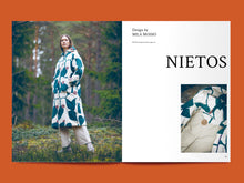 Load image into Gallery viewer, Two-page magazine spread, left side shows lady in forest wearing a long coat with hood. Right side features title text "NIETOS" with close-up photo of inside jacket and hood detail