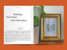 Load image into Gallery viewer, Two-page magazine spread, left side features title text "Breaking Stereotypes with Embroidery" above block of text. Right side features embroidered image of figures in embrace in frame
