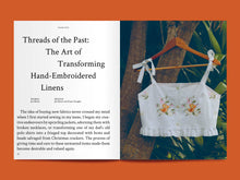 Load image into Gallery viewer, Two-page magazine spread, features image of a cropped cotton vest top with embroidery detail, on a wooden hanger, hanging from a tree branch. Left page features text article under the heading "Threads of the Past: The Art of Transforming Hand-Embroidered Linens".