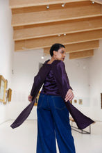 Load image into Gallery viewer, Model wears a long sleeved blouse with long scarf attachments details, in a modern indoor setting.