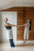 Load image into Gallery viewer, Two models handing hands leaning backwards, wearing sleeve-less tops with tie detail. One wearing the top in extended dress form