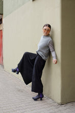 Load image into Gallery viewer, Lady stands against wall, raising a leg to show off wide legged trousers.